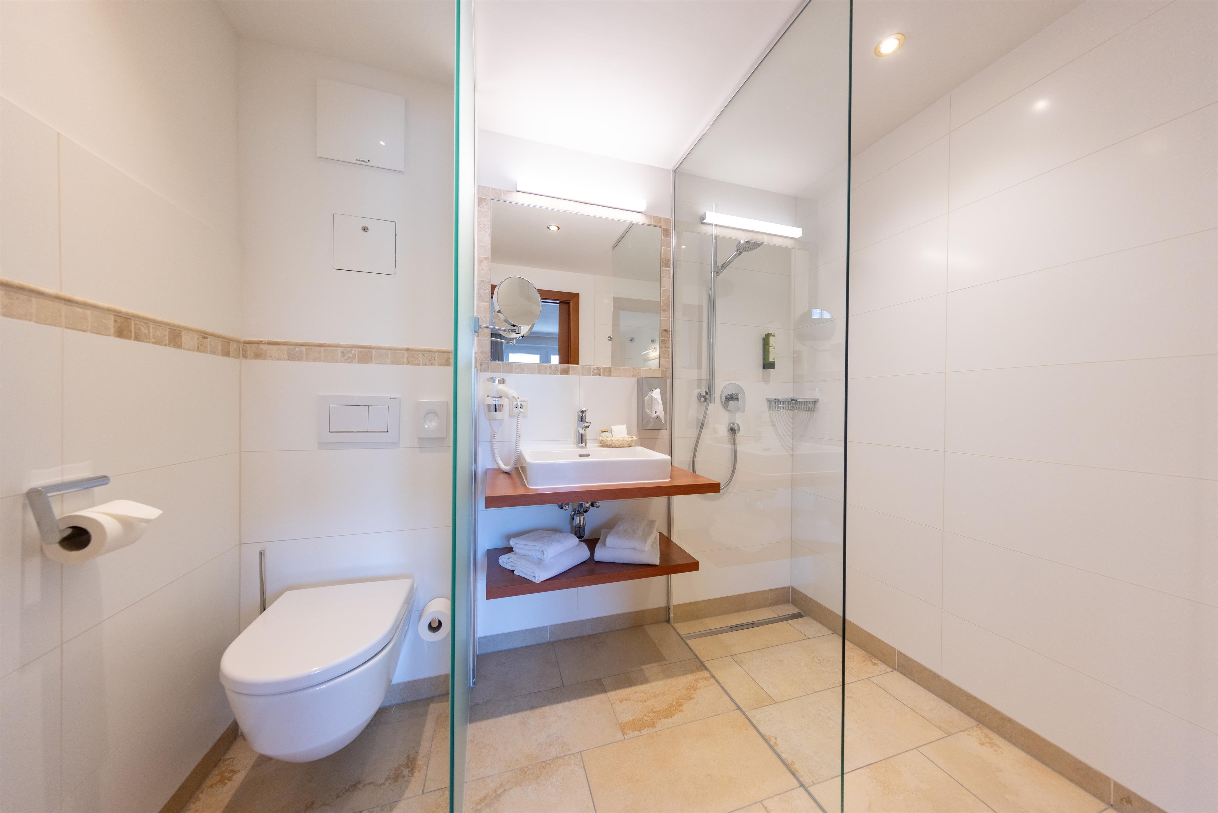 A modern bathroom with a glass shower and a stylish sink counter. The walls are painted in light colors, creating a pleasant atmosphere.