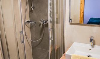 A modern bathroom with a glass shower enclosure and a sink. The colors are neutral, and the decor is clean and functional.