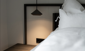 A modern bedroom with a cozy bed and a minimalist nightstand. A pendant light provides soft illumination.