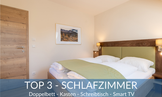 A modern bedroom with a double bed, dresser, and desk. There is a smart TV and plenty of natural light.