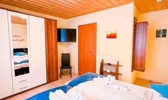 A cozy bedroom with a wooden ceiling and a large double bed. There is a wardrobe and a television on the wall.