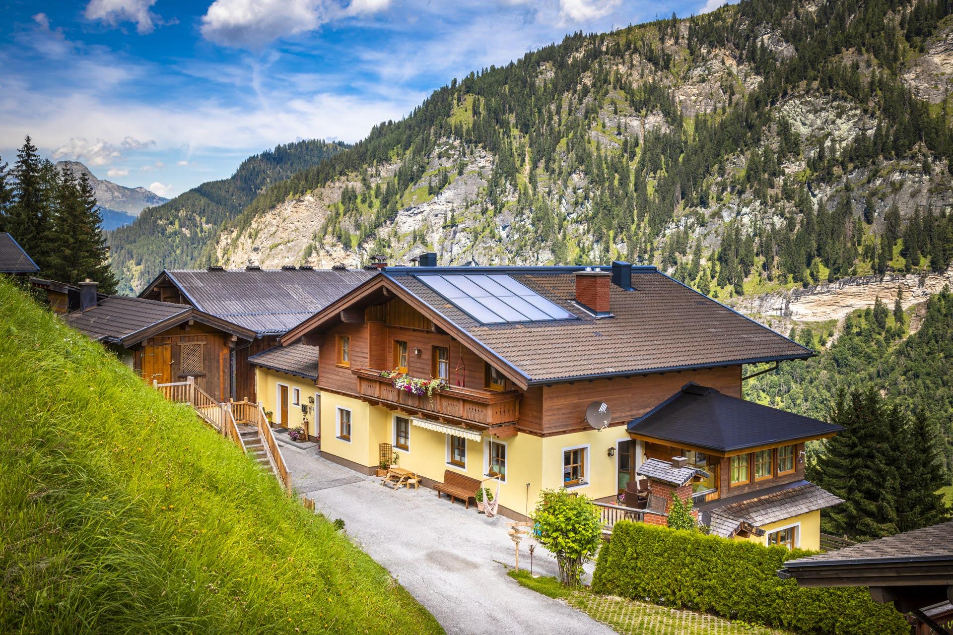 A cozy house in the mountains with a beautiful view of the surrounding forests. The environment is green and idyllic, perfect for a vacation in nature.