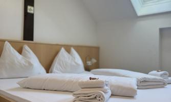 A cozy bedroom with a double bed and fresh towels. The room has a window that lets in daylight.