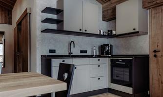 A modern kitchen with a wooden ceiling and bright furniture. The space is well-lit and offers a cozy dining area.