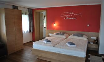 A comfortable bedroom with a double bed and modern furniture. The walls are painted in warm colors, and there is a large window with natural light.