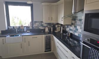 A modern kitchen with bright cabinets and a dark countertop. The window lets in plenty of daylight and offers a view outside.