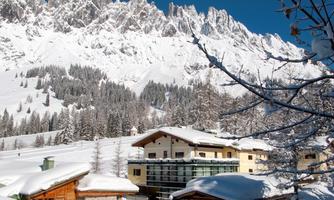A picturesque winter landscape with snow-covered mountains and modern chalets. The clear sky complements the tranquil, snowy scenery.