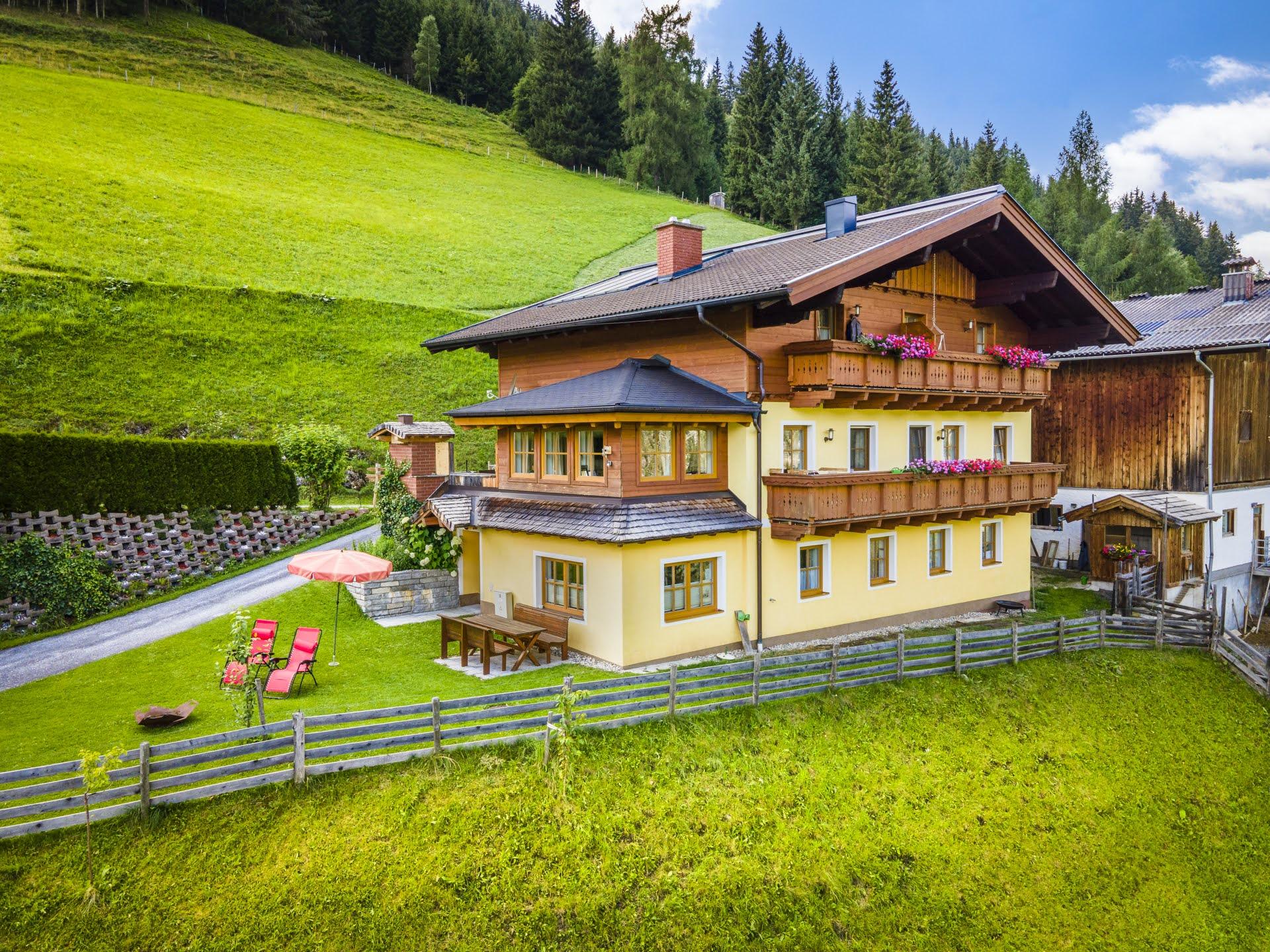 A charming house in nature with a green area and a view of the mountains. The garden is equipped with deck chairs and a sun umbrella.