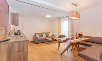 A modern living room with a comfortable sofa and a table. The decor is bright and inviting with a warm wooden floor.