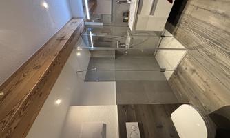 A modern bathroom with a glazed shower and elegant sanitary fittings. Wooden and tiled surfaces create a stylish atmosphere.
