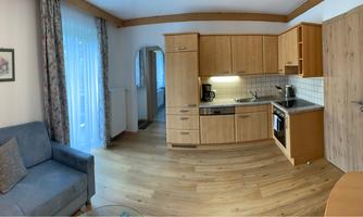 A modern apartment with an open kitchen and cozy living room. The space is bright and warmly furnished.
