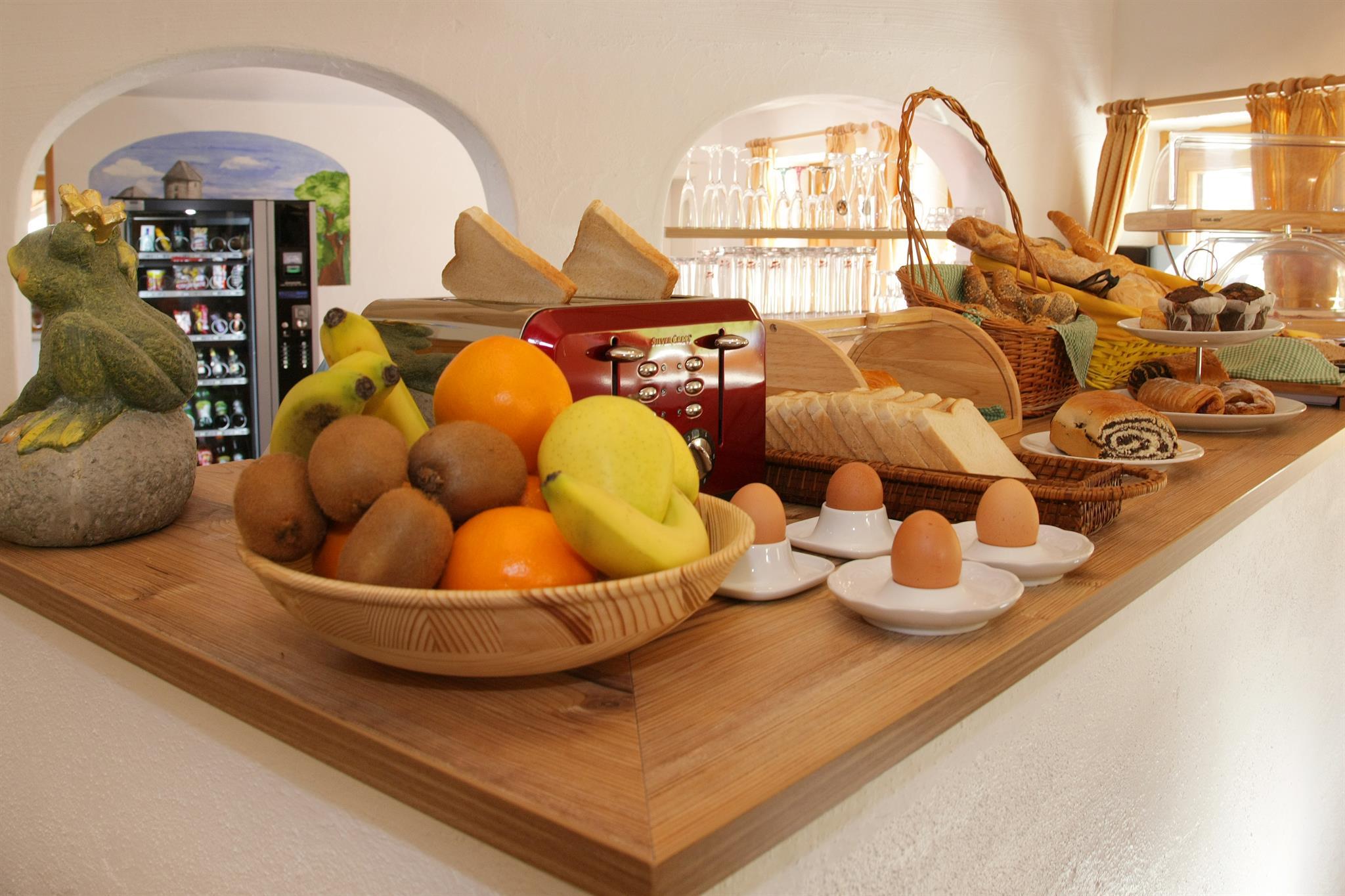 A rich breakfast buffet with fresh fruit, eggs, and various types of bread. The scene is bright and inviting.