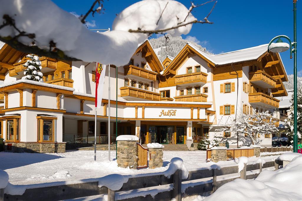 A charming alpine-style hotel, surrounded by snow and mountains. The clear blue sky perfectly complements the wintry landscape.