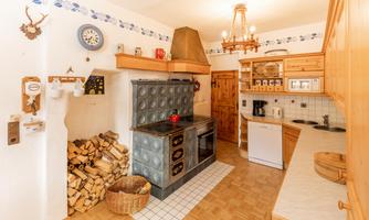 A cozy kitchen with a wood stove and ample storage space. The floor is designed with light wood and tiles.