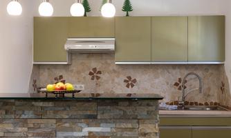 A modern kitchen with a green cabinet and a stone countertop. Fresh fruits are in a bowl on the table.