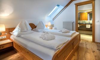 A cozy bedroom with a double bed and two nightstands. The room has light walls and wooden details, as well as an adjacent bathroom.
