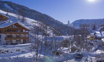 A picturesque winter landscape with snow-covered hills and charming houses. The sky is clear and the sun is shining brightly.