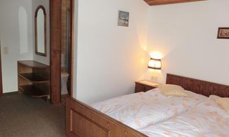 A cozy bedroom with two beds and wooden interior. There is a mirror and a small table in the room.