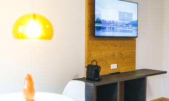 A modern living room with a television on the wall and a stylish table. A decorative lamp provides warm light.