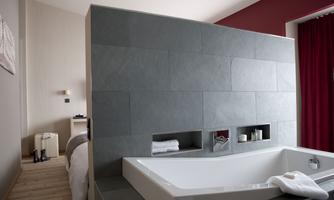 A modern bathroom with a freestanding bathtub. The walls are elegantly designed in gray stone and warm tones.