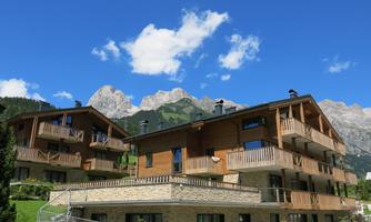 A charming wooden architecture in a picturesque mountain landscape. Majestic mountains rise in the background under a clear blue sky.