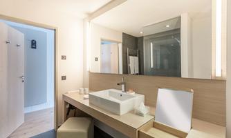 A modern bathroom with an elegant sink and large mirrors. The walls are light, and the room feels welcoming and inviting.