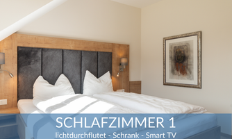 A bright bedroom with a large double bed and a modern wardrobe. There is also a piece of art on the wall and plenty of daylight.
