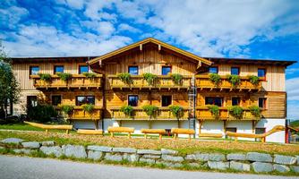 A charming wooden building with several balconies adorned with plants. The surroundings are green and natural, ideal for a relaxing stay.