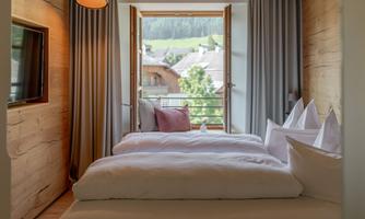 A bright bedroom with two beds and a view of the landscape. Large windows let in plenty of daylight and provide a beautiful view.