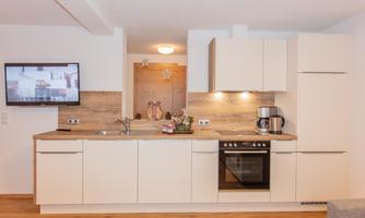 Modern kitchen with bright cabinets and wooden countertop. It is equipped with a stove, oven, and a coffee machine.