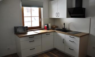 A modern kitchen with white cabinets and wood surfaces. It is well equipped with a microwave and sink.