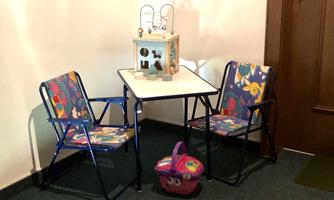 A small table with two colorful chairs and a toy. Next to the table is a small basket.