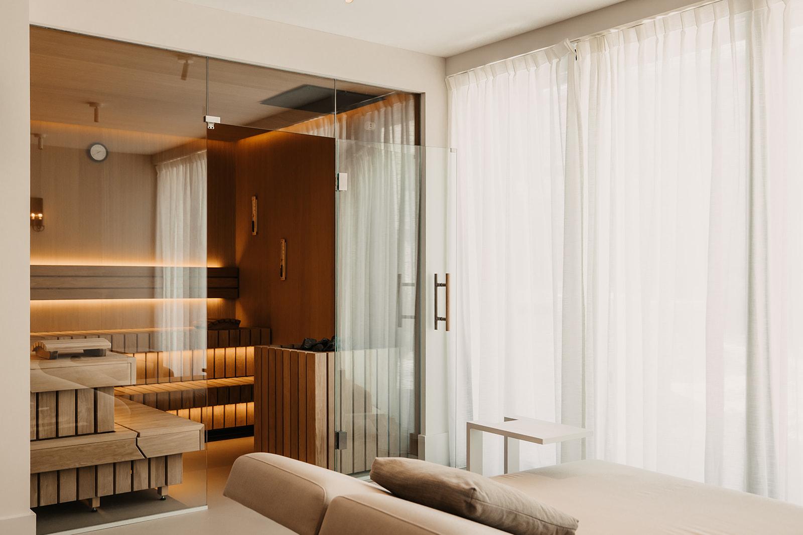 A modern room with elegant furnishings and large windows. The bright space has a cozy atmosphere with wooden accents.
