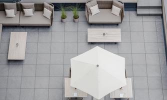 A modern terrace with comfortable seating and tables. A large umbrella provides shade and there are decorative plants.