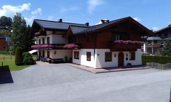 A beautiful alpine house with colorful flower balconies. It is situated in a quiet environment with a clear blue sky.