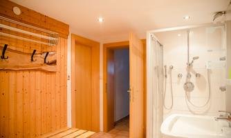 A cozy entrance area with wooden details and a bathroom. The bathroom has a shower and a bathtub.