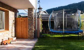 A beautiful garden with a trampoline and a view of the mountains. The terrace is tiled and has a pleasant, sunny ambiance.