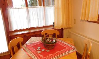 A cozy dining area with a wooden table and chairs. On the table, there is a basket with decorations.