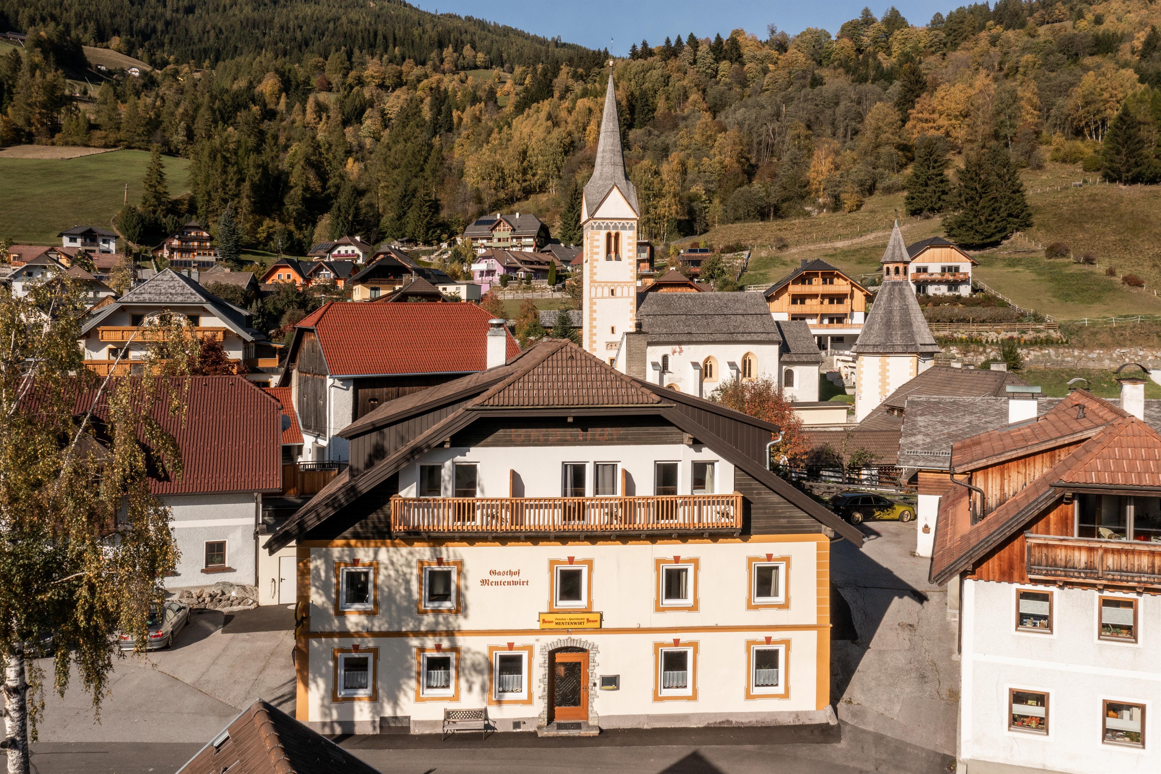 A picturesque German town with traditional buildings and a church. Surrounded by colorful trees and green hills.
