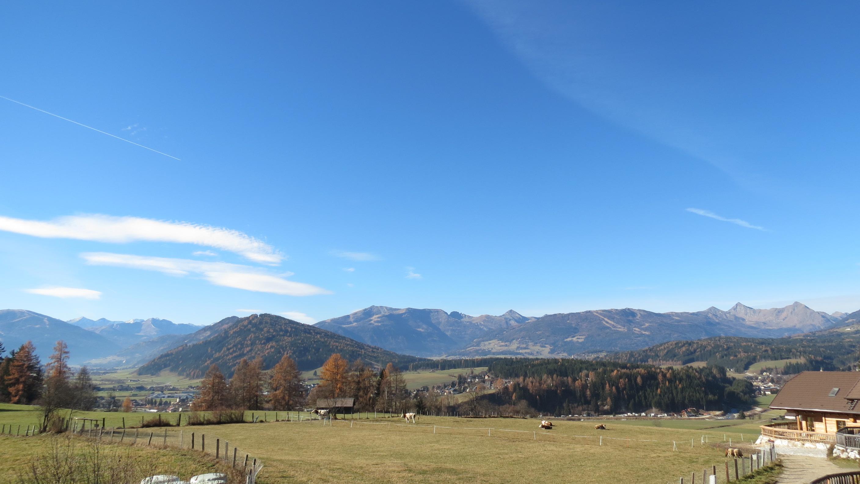A picturesque landscape with gentle hills and impressive mountains. The clear sky and sunny colors create an inviting atmosphere.