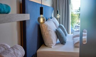 A modern bedroom with a comfortable bed and cozy pillows. The soft lighting creates an inviting atmosphere.
