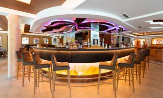 A modern bar with a stylish, round counter and illuminated accents. The seating is made of wood and creates an inviting atmosphere.