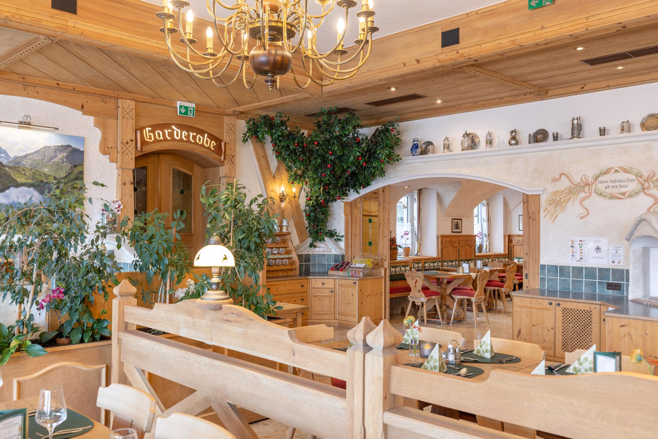 A cozy restaurant with wooden decor and plants. The atmosphere is warm and inviting, ideal for meals and social gatherings.