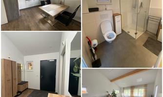 A modern room with a desk, a cozy living area, and a bathroom. There are bright walls, wooden flooring, and a pleasant atmosphere.