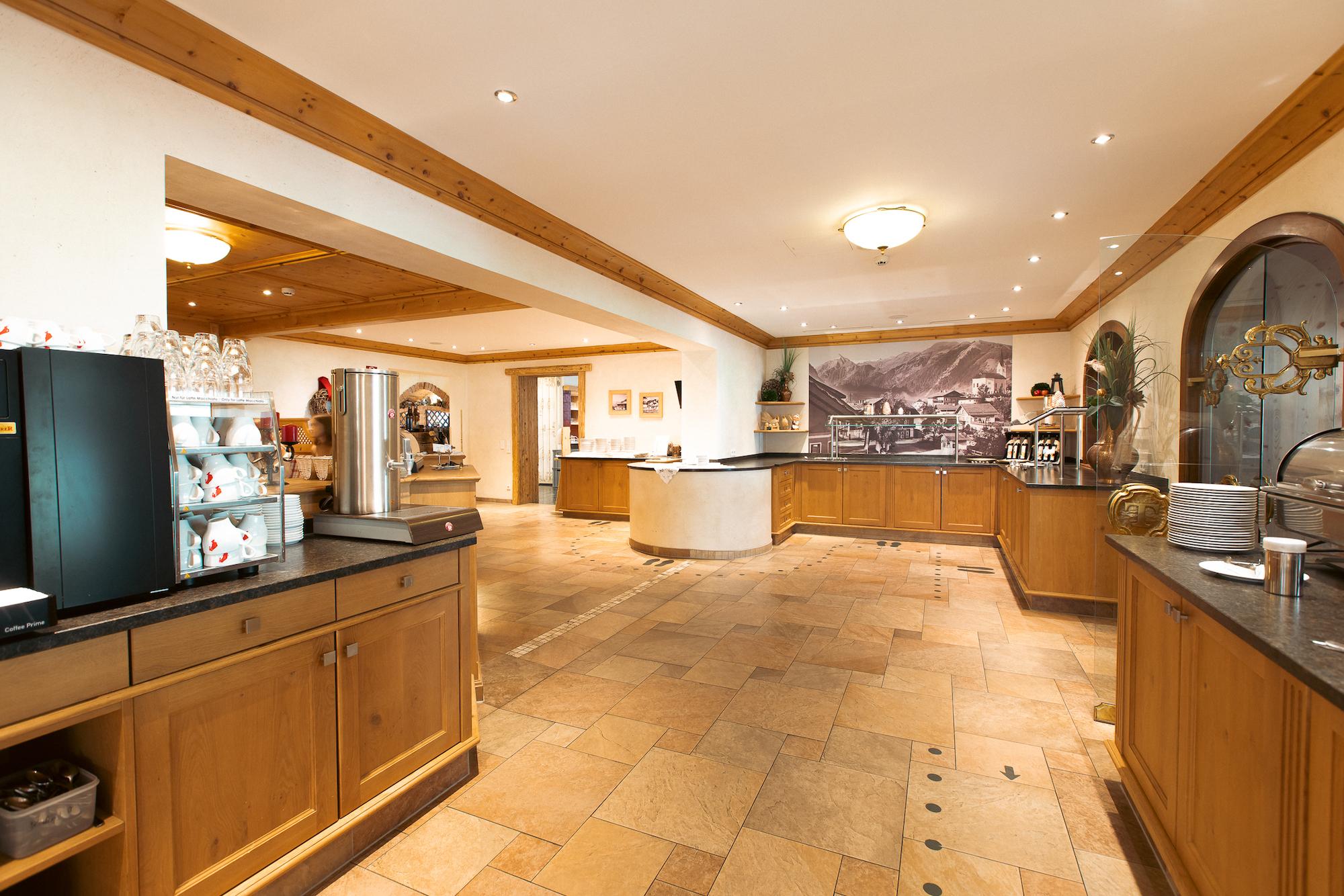 A cozy room with wooden cupboards and a central table. The atmosphere is welcoming and well-lit.