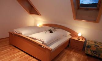 A cozy bedroom with a large double bed and soft lights. A window in the roof area lets natural light in.