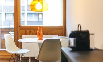 A modern dining room with a round table and white chairs. A striking orange vase and a stylish pendant light create an inviting atmosphere.