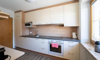 A modern kitchen with bright cabinets and a wooden countertop. There is a stove, a kettle, and a window with natural light.