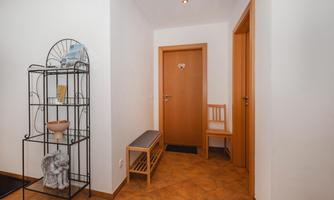 A bright hallway with a beige-colored floor. A beautiful metal rack and a wooden bench give the space an inviting atmosphere.