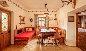 A cozy room with wooden furniture and a large table. The walls are adorned with traditional decorations.